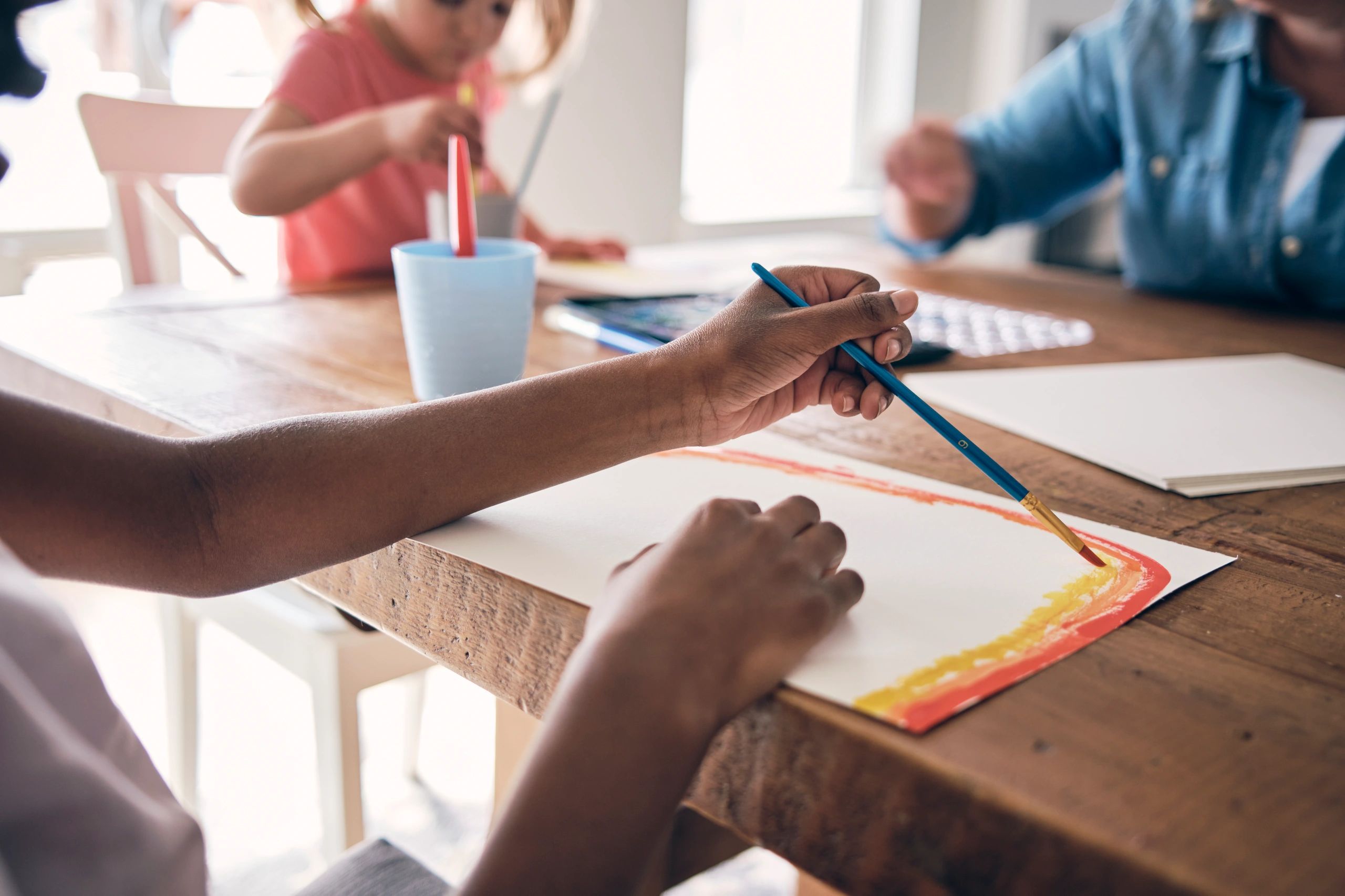 Children watercolor painting together at a table